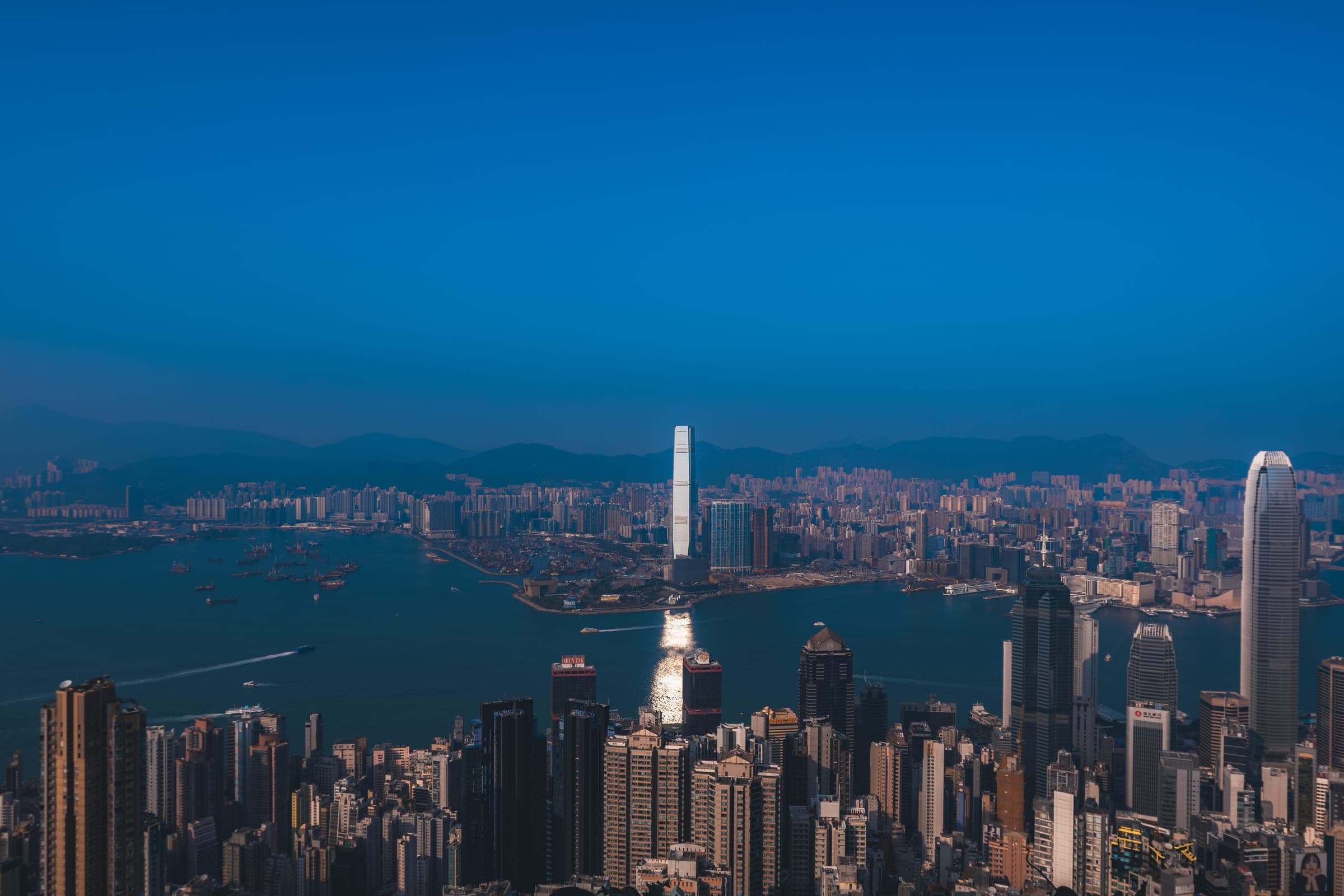 A harbour city of skyscrapers seen from above in blue evening light