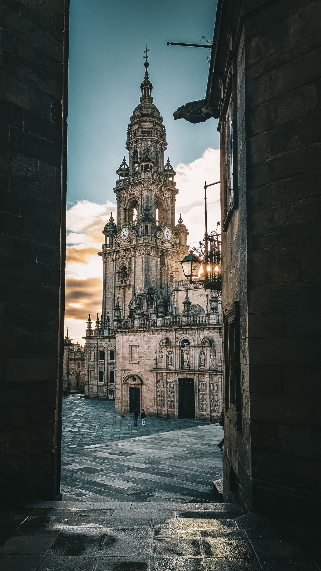 A baroque cathedral tower seen from a narrow stone passage