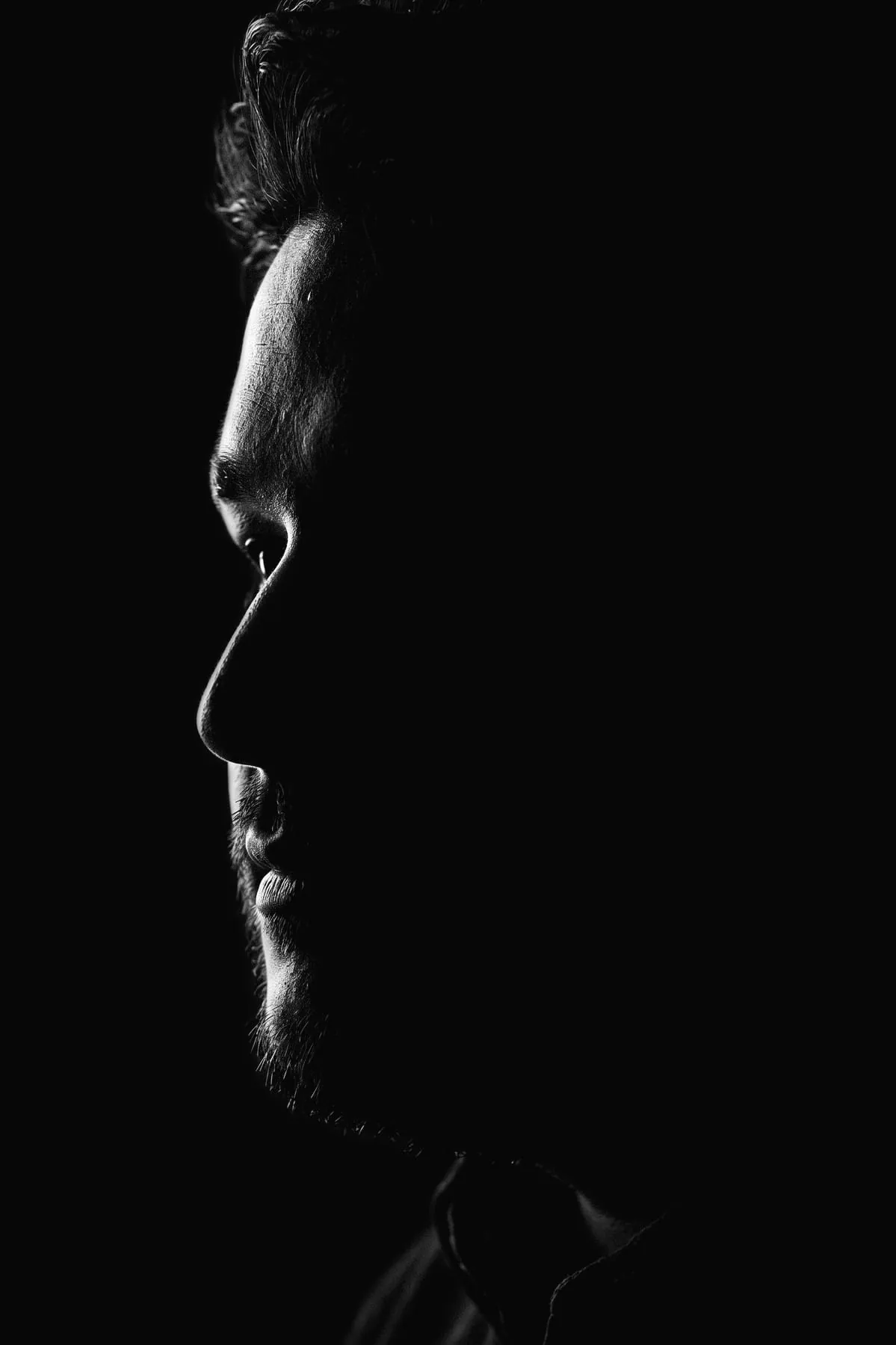 Arsen Dzantiev de perfil, a contraluz sobre fondo negro